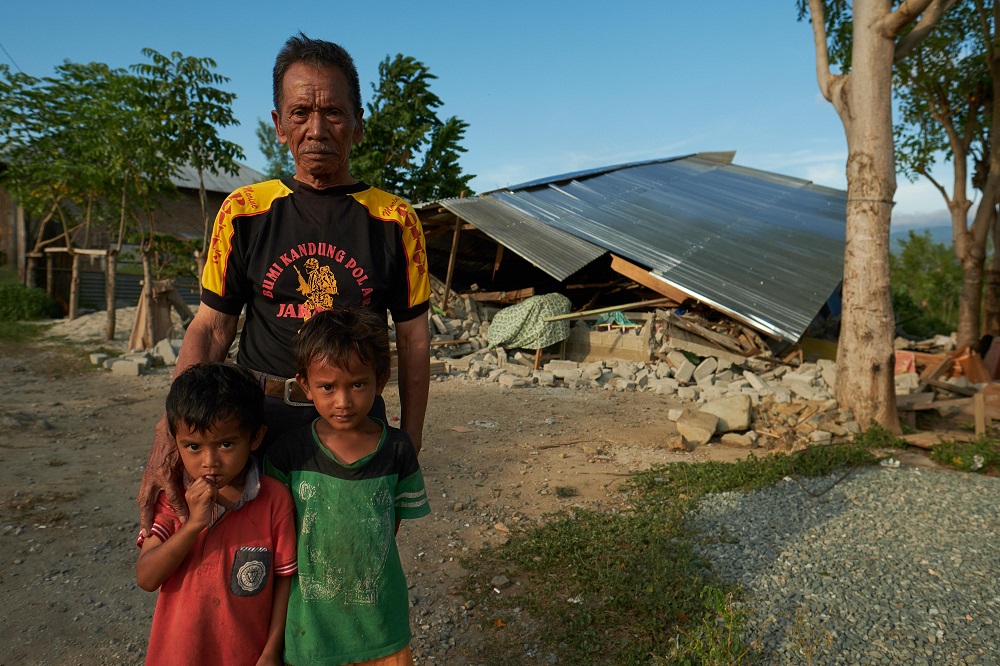 _475_https://www.helpage.org/silo/images/misini-77-and-his-grandsons-stand-in-front-of-their-demolished-home-just-outside-of-palu-city-in-indonesia-after-the-earthquake_1000x666.jpg